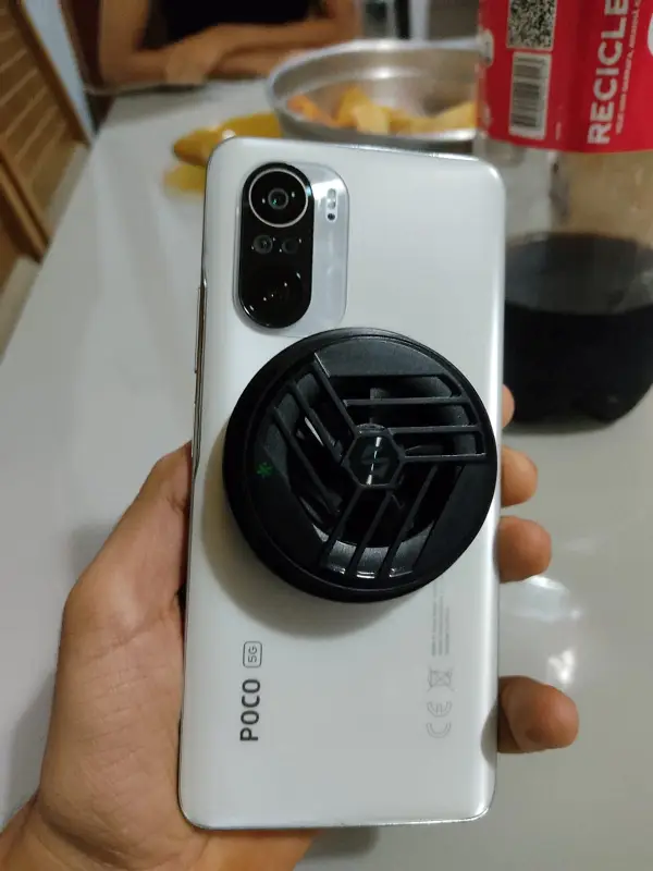 Imagem de um smartphone com um cooler acoplado na sua traseira. 